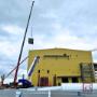 Crane lifting near yellow industrial building during system install. Crane lifting near yellow industrial building during system install.