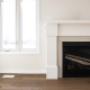 Wood fireplace mantel next to a window featuring baseboard and casing Wood fireplace mantel next to a window featuring baseboard and casing