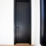 Black door with black casing around and black Weiser handle in living room with white walls and wood floors Black door with black casing around and black Weiser handle in living room with white walls and wood floors
