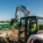 Bobcat Construction Equipment on a construction site moving pieces of material with a large machine with bucket attachment. Bobcat Construction Equipment on a construction site moving pieces of material with a large machine with bucket attachment.