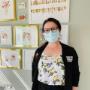 ID for accessibility: Shannen (our front desk person) is stood in front of our gallery of floral dental prints. She's wearing a black lab jacket, a white shirt with lemons on it and a blue medical mask. ID for accessibility: Shannen (our front desk person) is stood in front of our gallery of floral dental prints. She's wearing a black lab jacket, a white shirt with lemons on it and a blue medical mask.