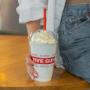 A close-up photograph of a woman holding a Five Guys milkshake. A close-up photograph of a woman holding a Five Guys milkshake.
