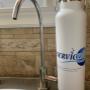 Bouteille d'eau réutilisable Serviceau à côté d'un système d'osmose inverse résidentiel. Bouteille d'eau réutilisable Serviceau à côté d'un système d'osmose inverse résidentiel.