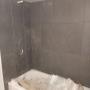 Ceramic tile is installed around tub in basement bathroom. Ceramic tile is installed around tub in basement bathroom.