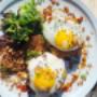 Breakfast plate at Volta Victoria featuring two sunny-side-up eggs topped with crispy onions and sesame seeds, served with house-made potato hash, fresh greens, and a drizzle of sauce. A colourful and hearty brunch option in downtown Victoria, BC. Breakfast plate at Volta Victoria featuring two sunny-side-up eggs topped with crispy onions and sesame seeds, served with house-made potato hash, fresh greens, and a drizzle of sauce. A colourful and hearty brunch option in downtown Victoria, BC.